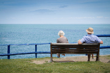 Elderly couple relaxing in front of the sea view. With copyspace above.