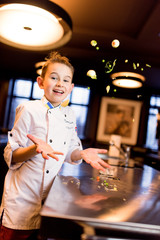 Little boy dressed like a cook has fun on the kitchen
