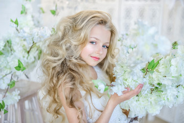 Beautiful little girl with long blonde hair poses in the studio