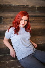 Young woman with red long hair indoor portrait on wooden background