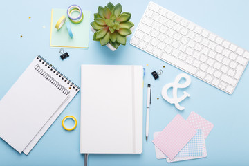 Workspace with keyboard, diary,pen,paper clips, stickers on trending blue background, flat lay