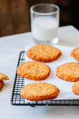 Old fashioned oatmeal cookies on a wire rack with galss of milk. Close up.