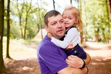 The father embracing her daughter and standing in the park