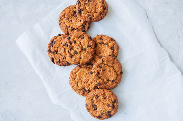 Traditional American homemade chocolate chips cookies on a wire rack on a white stone background.