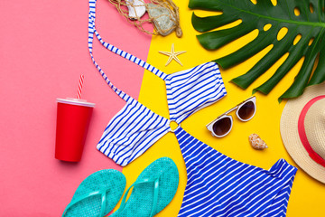 Fototapeta na wymiar Beachwear and accessories on a pink and yellow background