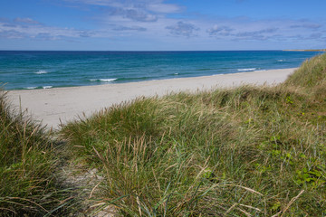 Fototapeta na wymiar Sandy dunes covered with a grass on lovely Sola Strand beach near Stavanger, Norway