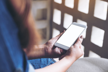 Mockup image of a woman holding white mobile phone with blank desktop screen in cafe