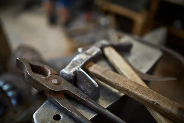 Obraz na płótnie Canvas Close-up of a blacksmith's hands manipulating a metal piece above his forge, selective focus.