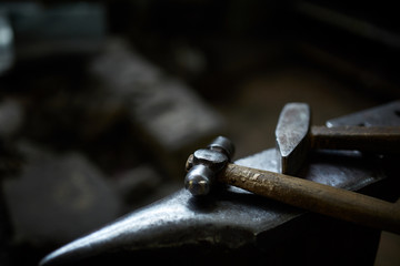 Close-up of a blacksmith's hands manipulating a metal piece above his forge, selective focus.