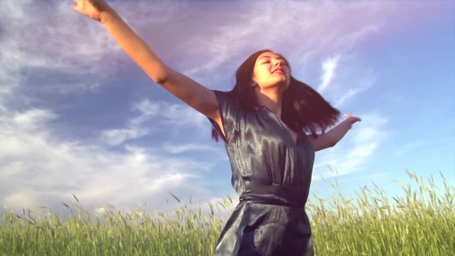 Beauty girl running and spinning on summer field, over sunset sky. Freedom concept. Happy young woman outdoors. Allergy free concept. Slow motion. 3840X2160 4K UHD video footage