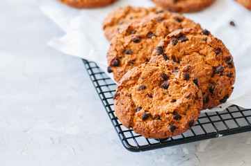 Homemade chocolate chips cookies on a wire rack on a white stone background. Traditional American old fashioned treats. Close up.