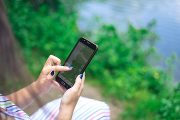 Woman tourist holds the phone with navigation. Walk in the summer forest