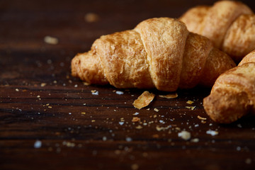 Tasty buttery croissants on an old wooden table, close-up, selective focus, shallow depth of field.