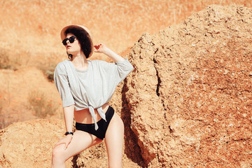 A beautiful girl in a straw hat walking on a mountainous terrain in the desert.
