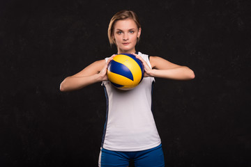 Girl playing volleyball on a dark background