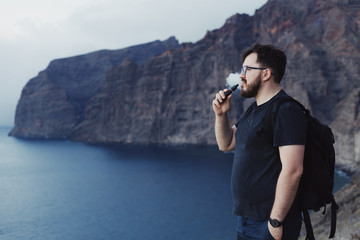 Man vaping ecigarette in front of the ocean