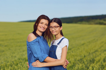 Mother and daughter teenager embrace in a field of wheat in nature.