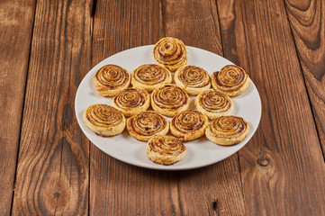 puff cookies with chocolate layer on white plate on wood background