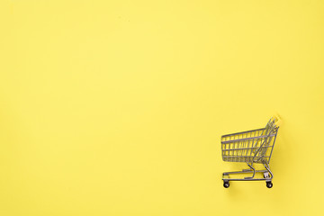 Shopping cart on yellow background. Minimalism style. Creative design. Top view with copy space. Shop trolley at supermarket. Sale, discount, shopaholism concept. Consumer society trend © jchizhe