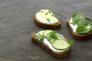 Bread with yogurt and cucumber on brown background.