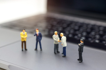 Miniature people: Businessman handshake to business success Online on laptop. Commitment,...