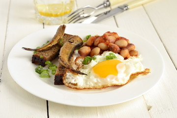 Breakfast with fried egg, beans, sprats