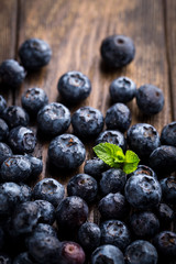 Close up of fresh blueberries with mint on rustic wooden background, overhead view