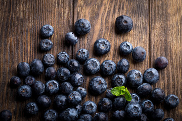 Close up of fresh blueberries with mint on rustic wooden background, overhead view
