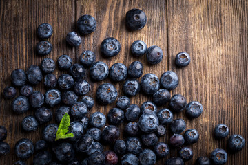 Fresh blueberries with mint on rustic wooden background, overhead view