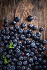 Fresh blueberries with mint on rustic wooden background, overhead view