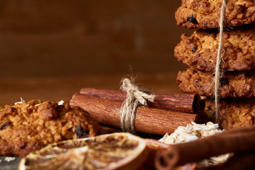 Christmas composition with chocolate biscuits, cinnamon and dried oranges on wooden background, close-up.