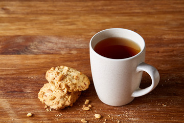 White porcelain mug of tea and sweet cookies on wooden background, top view, selective focus