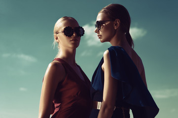 Two fashion models pose against the background of the Sunny sky - obrazy, fototapety, plakaty