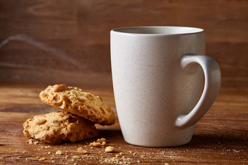 White porcelain mug of tea and sweet cookies on wooden background, top view, selective focus