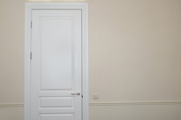 White door on a beige wall in an empty room. Details in the interior