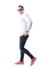Fototapeta premium Cool stylish elegant young adult man with sunglasses walking and looking at camera. Full body isolated on white background. 