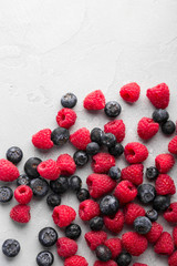 Fresh blueberries and raspberries on light concrete background, overhead view, copy space