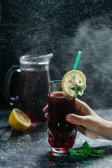 Cold refreshing berry drink with ice, mint and lemon close up