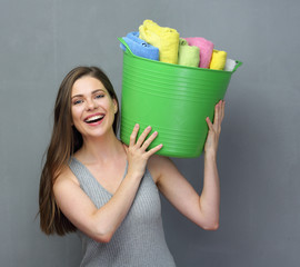 Smiling woman holding green basket with towels or clothes on sho