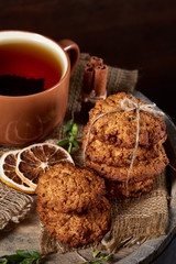 Traditional Christmas tea concept with a cup of hot tea, cookies and decorations on a wooden background, selective focus