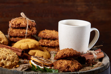 Traditional Christmas tea concept with a cup of hot tea, cookies and decorations on a wooden background, selective focus
