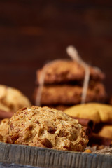 Conceptual composition with assortment of cookies and cinnamon on a wooden barrel, selective focus, close-up