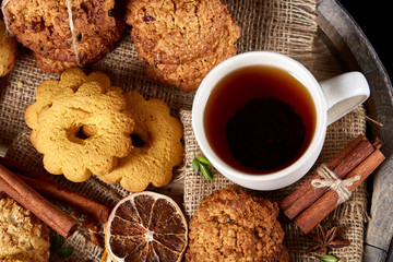 Traditional Christmas tea concept with a cup of hot tea, cookies and decorations on a wooden background, selective focus