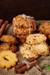 Conceptual composition with assortment of cookies and cinnamon on a wooden barrel, selective focus, close-up