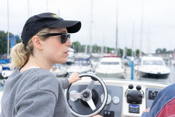 Daughter driving a motor cruiser out to sea with her father