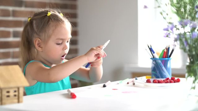 Small little girl draws picture at the table. Close up 4K shot.