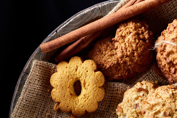 Conceptual composition with assortment of cookies and cinnamon on a wooden barrel, selective focus, close-up