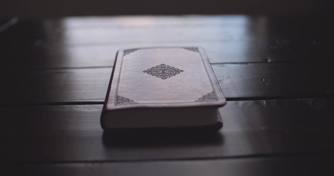 Brown Bible laying on top of wooden table.