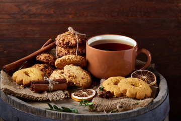 Traditional Christmas tea concept with a cup of hot tea, cookies and decorations on a wooden background, selective focus