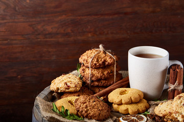 Traditional Christmas tea concept with a cup of hot tea, cookies and decorations on a wooden background, selective focus
